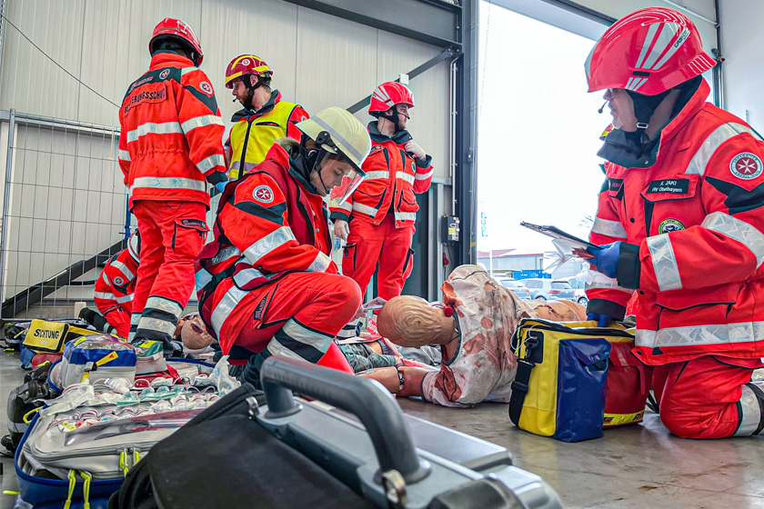 Johanniter in Einsatzkleidung führen an Puppen erste Hilfe durch.