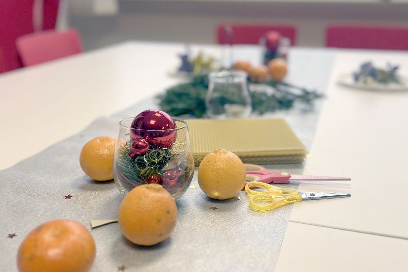 Ein Tisch ist weihnachtlich geschmückt mit Glitzer-Tischdecke, Christbaumkugeln und Orangen.