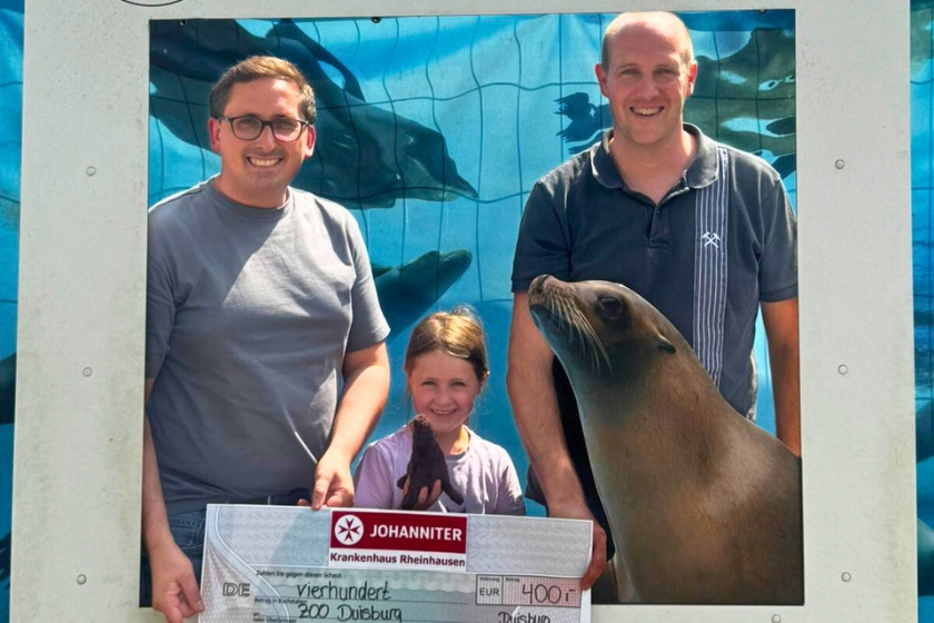 Spendenübergabe ZOO Duisburg- vor dem Bauzaun der Seelöwenanlage von links nach rechts: Christian Schreiner, Referent Sponsoring und Öffentlichkeitsarbeit, Julia Riering, Andreas Riering, Leitung Therapiezentrum