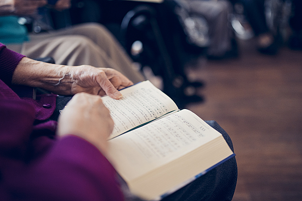 Ein Gesangbuch liegt aufgeschlagen auf dem Schoß einer Bewohnerin