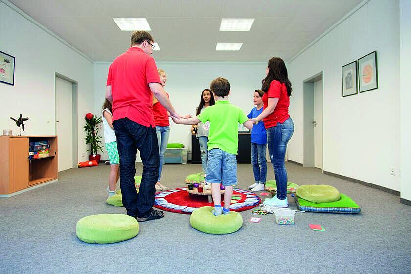 Kinder und Erwachsene stehen in einem Kreis