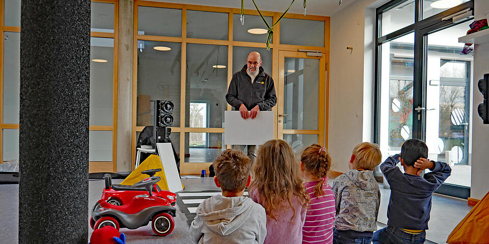 Ein Mann in einer Kita erklärt Kindern etwas