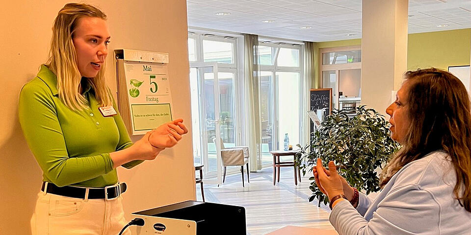 Zwei Frauen stehen sich gegenüber; zwischen ihnen auf einem kleinen Tisch eine Box, die von innen schwarz ist.