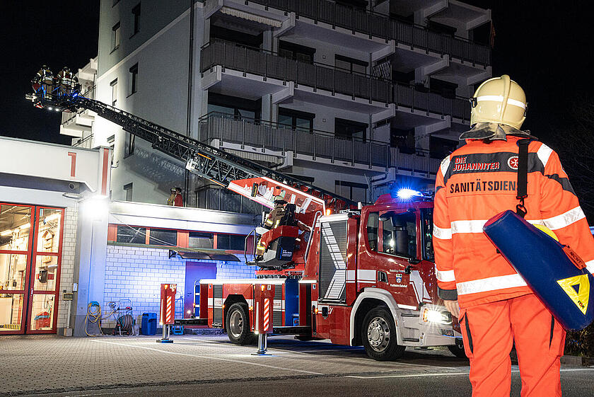 Ein Johanniter Sanitäter blickt auf ein Feuerwehr Auto.