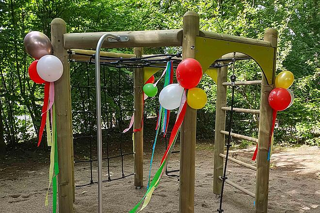 Ein Klettergerüst ist mit Ballons und Luftschlangen dekoriert.