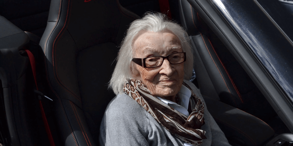 Eine weißhaarige alte Dame sitzt auf dem Beifahrersitz