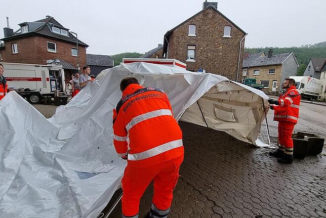 Einsatzkräfte der Johanniter bauen nach der Ahrtalflut in Stolberg ein Stangenzelt auf.