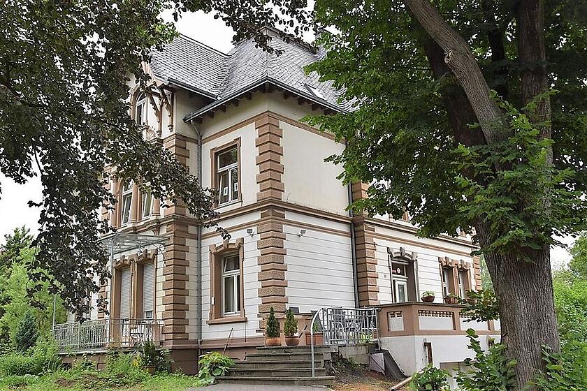 Eine alte Villa mit großen Bäumen.