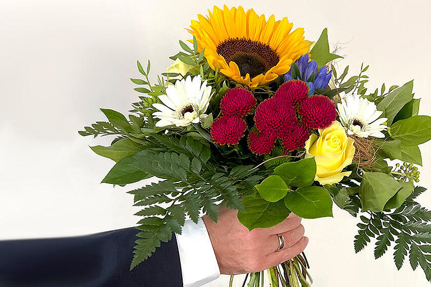 Glückwunsch mit Blumenstrauß zum Dienstjubiläum