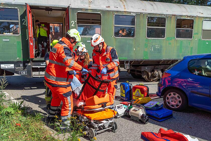 Einsatzkräfte der Schnell-Einsatz-Gruppe Sanität legen eine verletzte Person auf eine Trage.