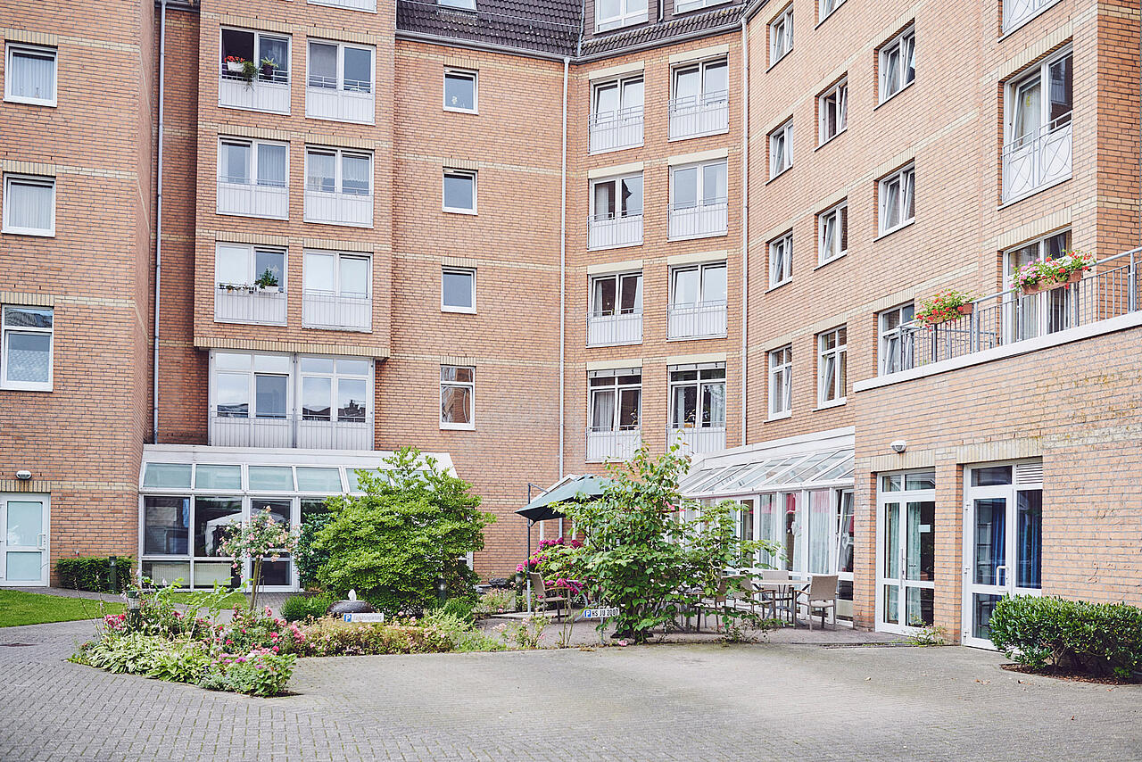 Hausblick mit Sitzgelegenheiten und angelegte Blumenbeete im Johanniter-Stift Erkelenz