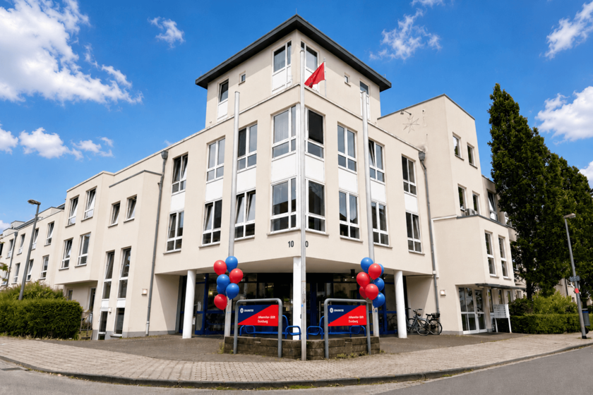 Johanniter-Stift Duisburg-Neudorf – Gebäudeansicht. großes Gebäude mit Flachdach an einer Straßenecke, hellbeige mit weißen Fensterrahmen. 