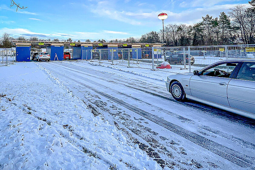 Ein Auto fährt auf einer von Schnee bedeckten Straße auf ein Impf-Drive-Through zu.