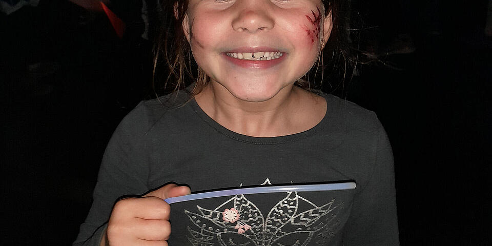 Ein lachendes Kind mit einer geschminkten Wunde an Halloween im Juhte-Laune-Zirkuszelt