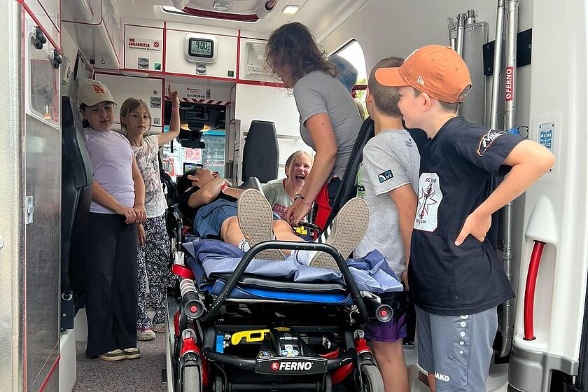Schulkinderbekommen das Innere eines Rettungsdienstfahrzeugs erklärt