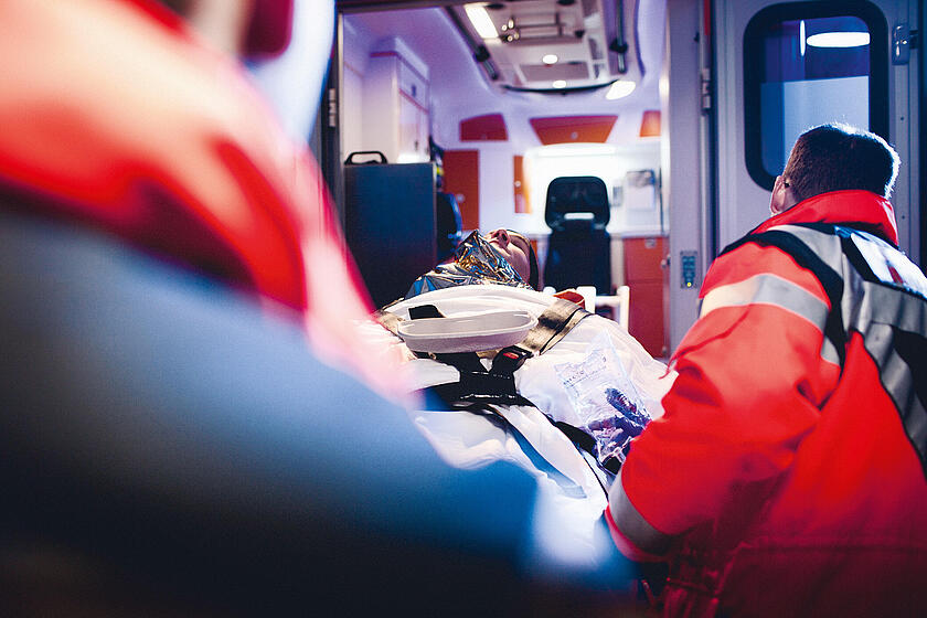 Eine Person wird von Einsatzkräften in einen Rettungswagen befördert.