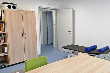 Bild vom Therapieraum der Ergotherapie mit Therapiematerial und Behandlungsliege