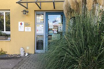 Die Eingangstür zum Mehrgenerationenhaus mit einem großen Busch an der Seite.