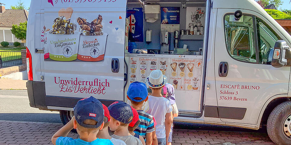 Kinder in einer Schlange vor einem Eiswagen