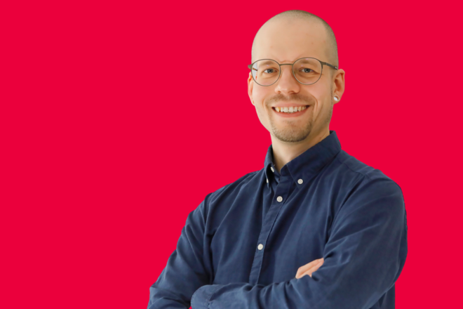 Portrait eines Mitarbeiters vor rotem Hintergrund