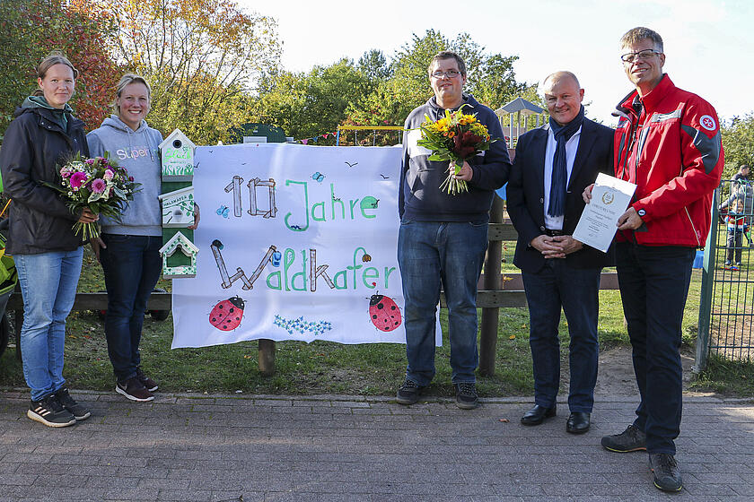 Nadja Schubring, Nicole Thele, Tobias Pieberg, Bürgermeister Jürgen Lamp und Johanniter-Bereichsleiter Peter Küpper (v.l.) feiern gemeinsam mit Team, Kindern und Eltern das zehnjährige Bestehen der Waldkäfer.