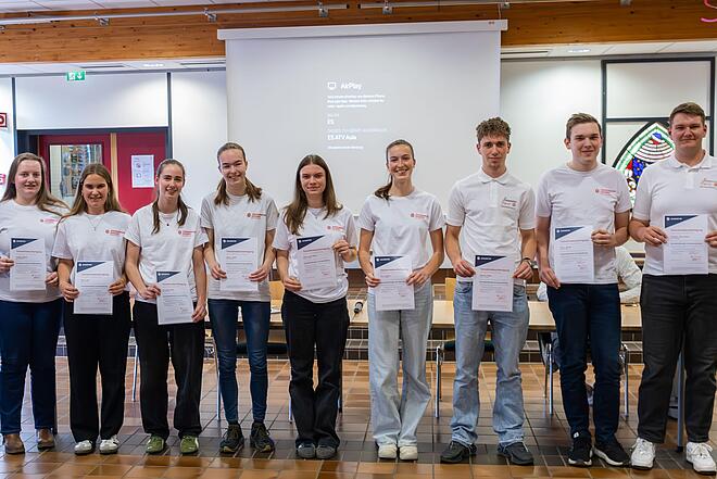 Personengruppe Schülerinnen und Schüler mit Urkunden in den Händen