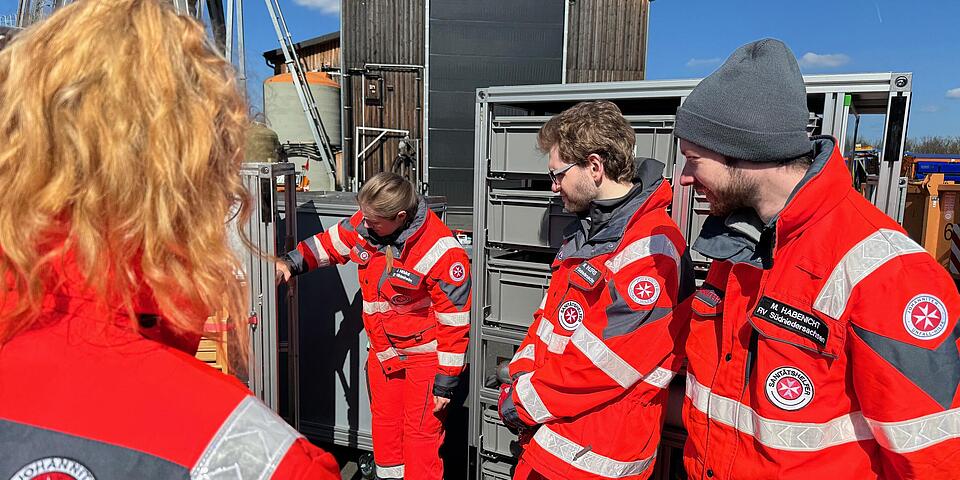 Johanniter schauen in einen Rollcontainer
