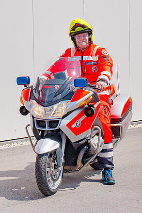 Ein Johanniter sitzt auf einem Johanniter Einsatzmotorrad.