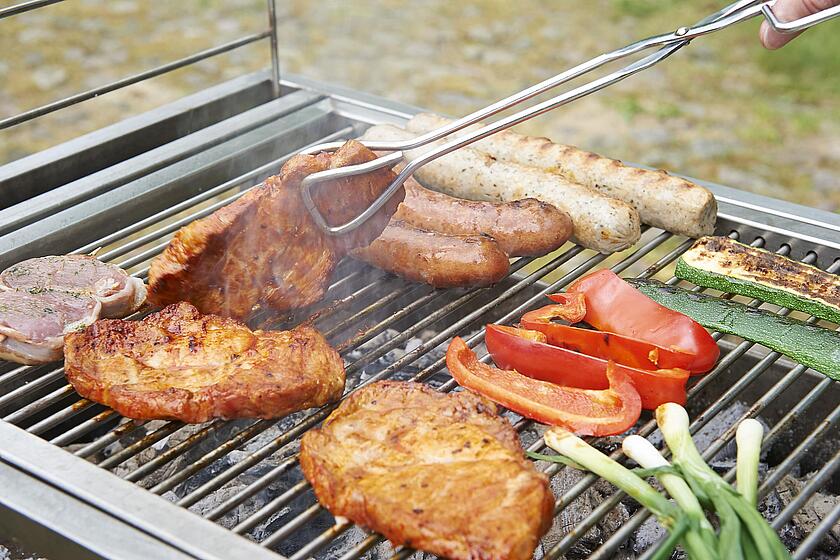 Auf einem Grill wird Fleisch und Gemüse gegrillt.