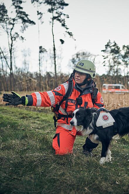 Rettungshundeteam sucht am Waldrand nach einer vermissten Person.