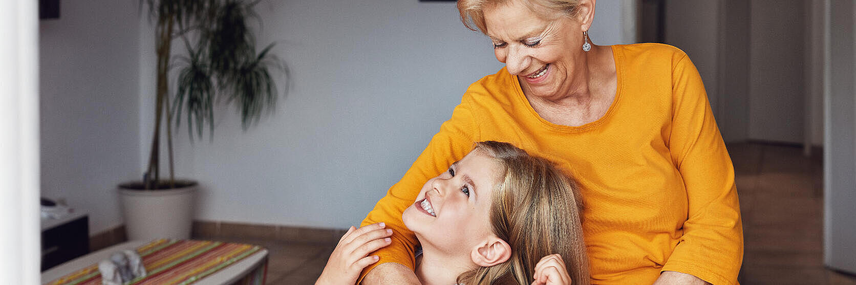 Eine Großmutter mit ihrer Enkelin. Die Oma trägt einen Hausnotruf-Sender am Handgelenk.