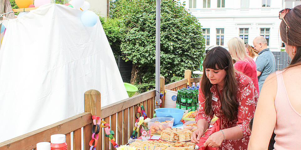 Ein Büffet mit verschiedenen Speisen. Eine frau im roten Kleid bedient sich.