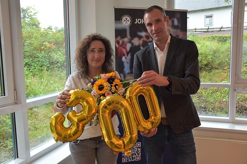 Regionalvorstand Alexander Knoop überreicht Vanessa Martin als 300. Mitarbeitende bei den Johannitern einen Blumenstrauß