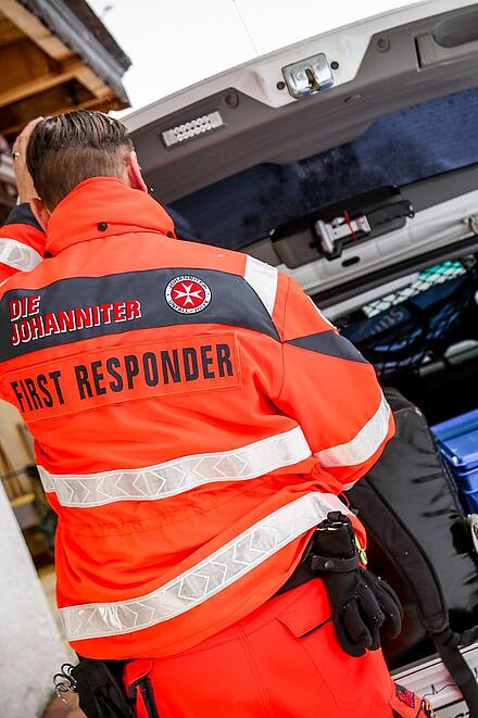 Sanitäter der Johanniter entnimmt am geöffneten Kofferraum Material.