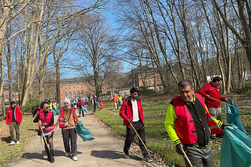 Bewohnende und Mitarbeitende der Landesunterkunft Kiel sammeln Müll in der Wik ein.