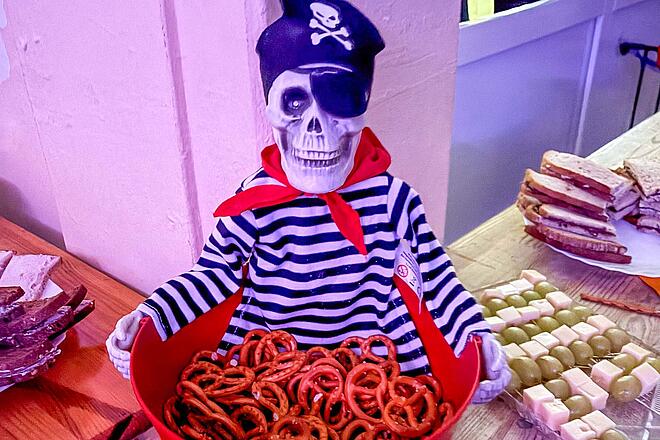 Halloweenparty in der Kita Traumland Das Buffet bei der Halloween-Party in der Johanniter-Kita Traumland wurde von den Eltern der Kinder organisiert. Ein Figur (Skelett-Pirat) hält eine Schüssel mit Mini-Brezeln.