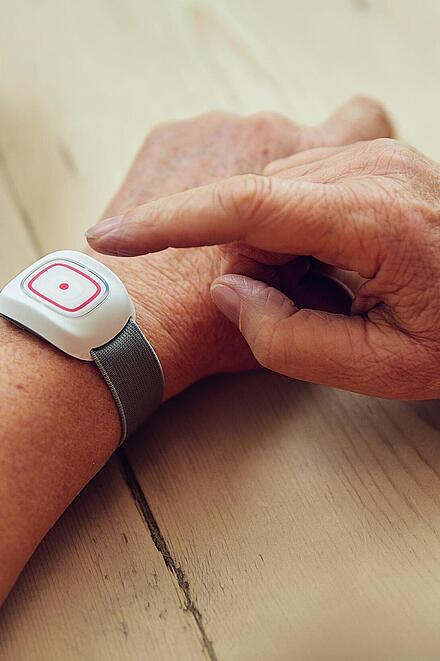 Hausnotrufsender am Arm wird gedrückt