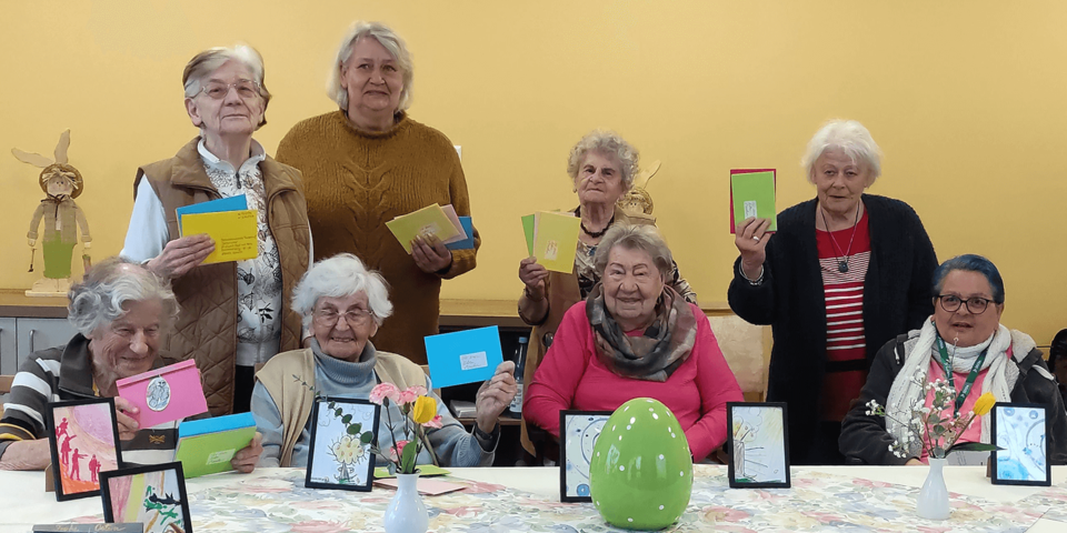 acht stehende und sitzende Menschen zeigen Osterpost