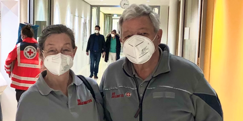 Zwei Johanniter-Helfer mit Masken stehen in einem Krankenhausflur.