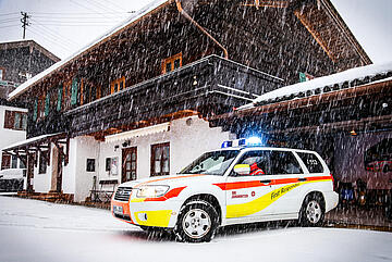 Johanniter-Einsatzfahrzeug startet bei Schnee aus der Garage zum Notruf