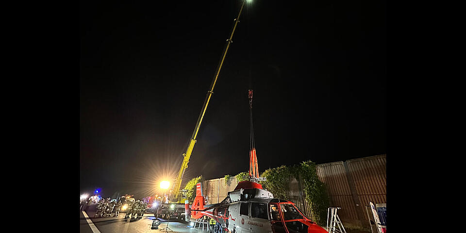 Hubschrauber wird mit einem Kran auf den Tieflader verfrachtet.