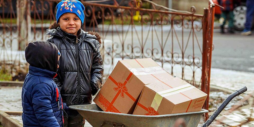Eine Frau transportiert ein Weihnachtstruckerpaket mit einer Schubkarre