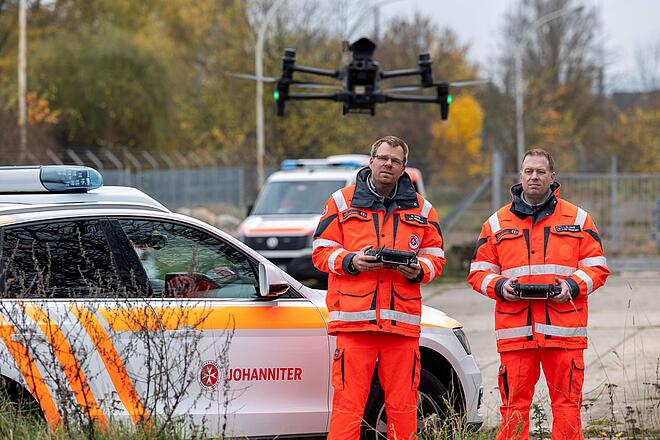 Zwei Männer mit einer vor ihnen schwebenden Drohne