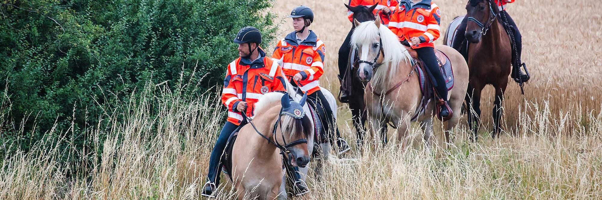 Mehrere Einsatzkräfte der Johanniter sitzen auf Pferden.