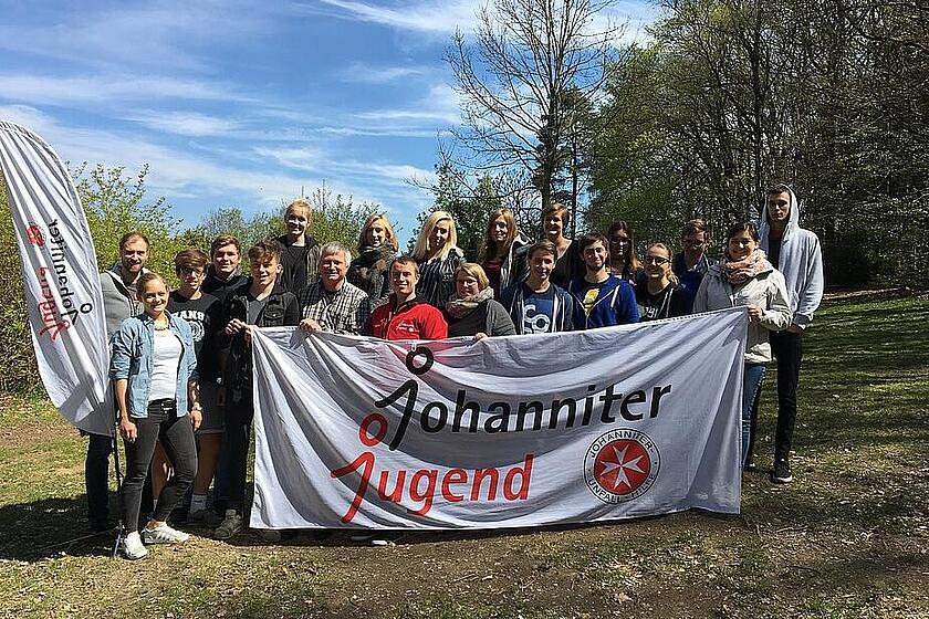 Ein Gruppenbild von Jugendlichen mit einem Johanniter-Jugend-Banner vor der Gruppe