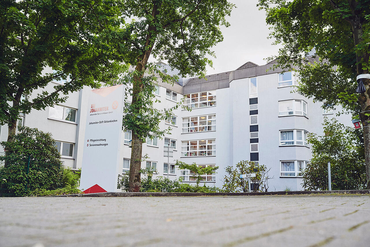 Blick vom Parkplatz auf die helle Seitenfront mit vielen Fenstern vom Johanniter-Stift Gelsenkirchen