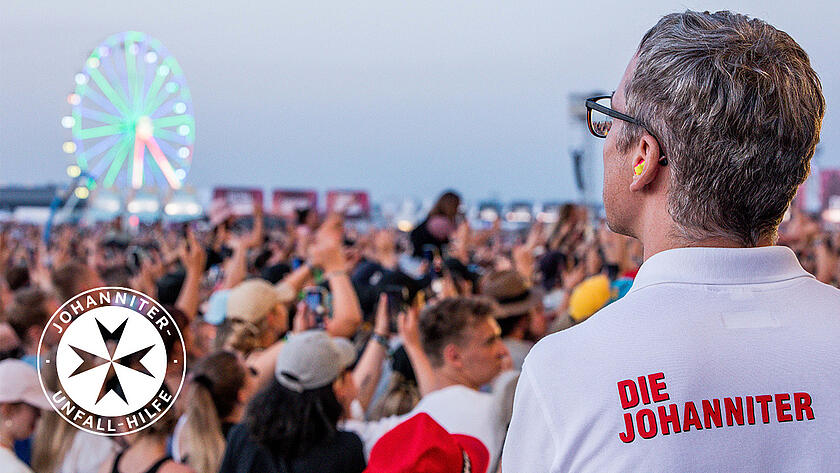 Titelbild für Aftermovie: Johanniter ist von hinten zu sehen und blickt auf feierndes Publikum