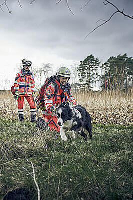 Zwei Frauen mit Einsatzkleidung und ein Hund im Gelände