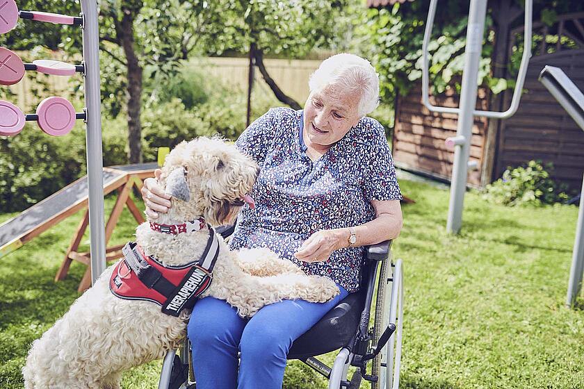 Eine Bewohnerin streichelt einen Therapiehund