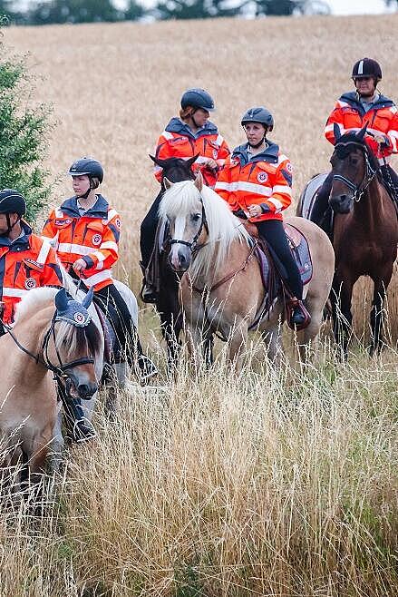 Mehrere Einsatzkräfte der Johanniter-Reiterstaffel sitzen auf Pferden.